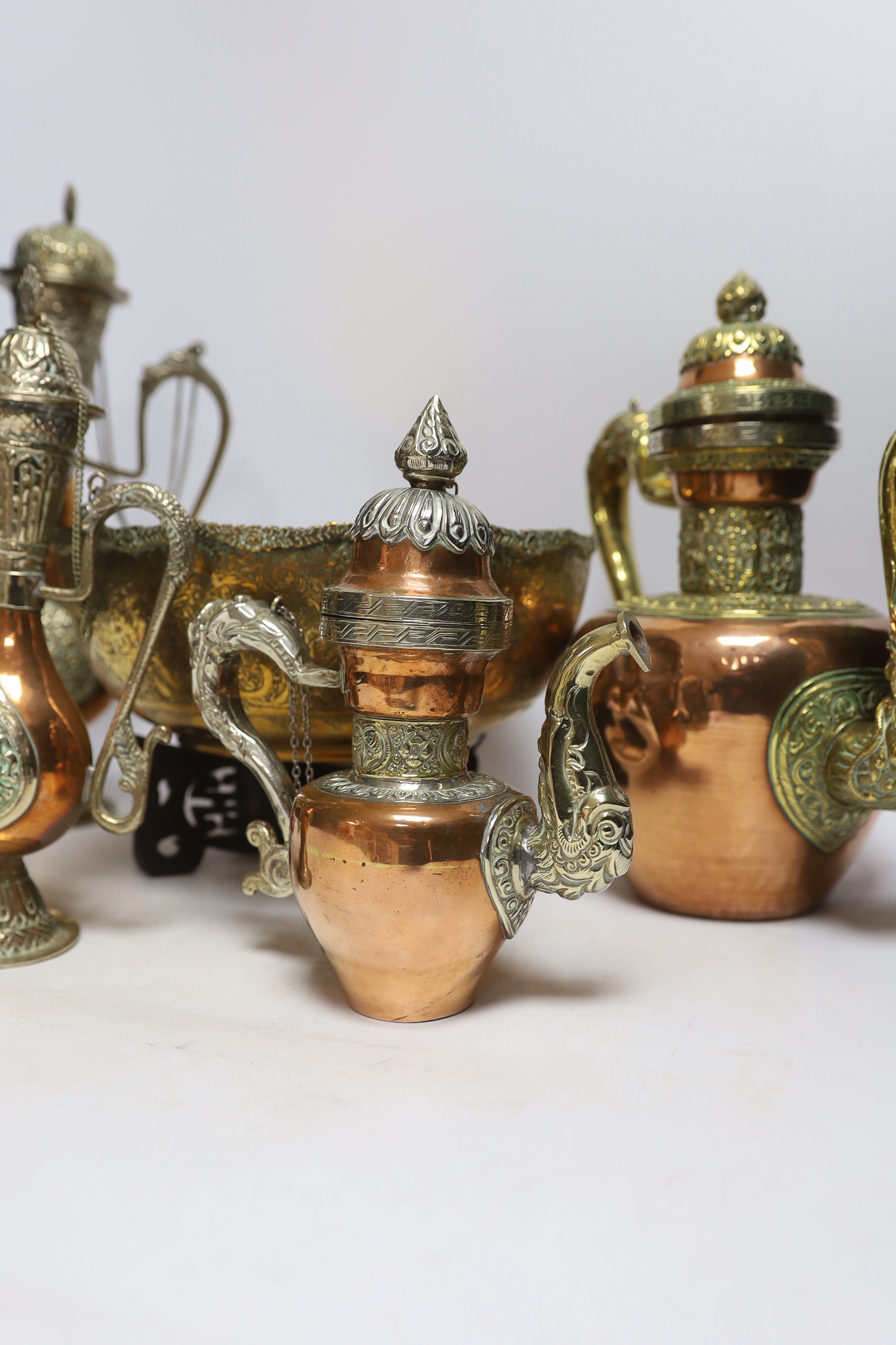 Four Tibetan overlaid copper teapots and an engraved brass bowl, tallest 34cm